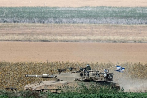 An Israeli army tank moves in a field in southern Israel near the Gaza border