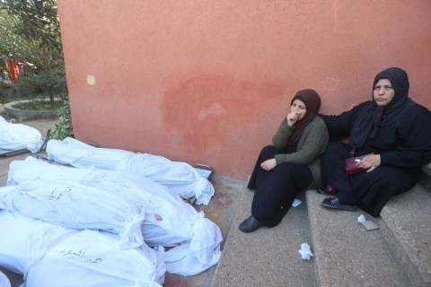 Women sit next to shrouded bodies of relatives killed following Israeli strikes at Khan Yunis's Nasser hospital