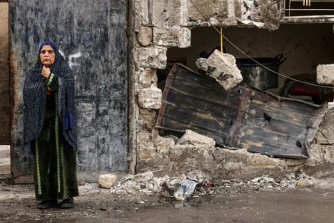 A woman stands outside a house destroyed in Israeli bombardment in Rafah, in the southern Gaza Strip, on December 20, 2023