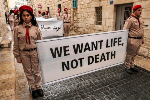 Palestinians in Bethlehem hold up banners calling for an end to the conflict