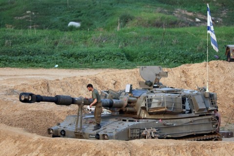 An Israeli soldier carries out maintenance on a Howitzer self-propelled artillery vehicle on the border with the Gaza Strip on December 27, 2023