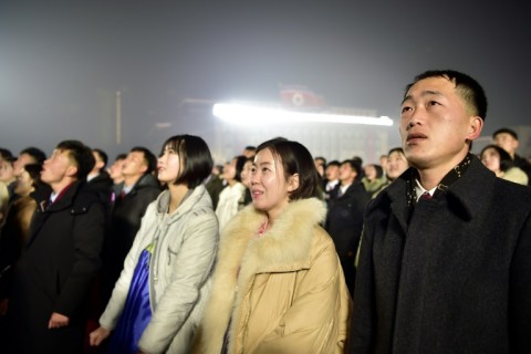 People watch as the North Korean flag is raised during a ceremony to welcome in the new year at Kim Il Sung Square in Pyongyang on January 1, 2024