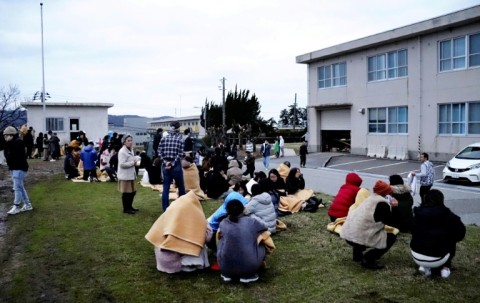 People sit outside after evacuating buildings in the city of Wajima