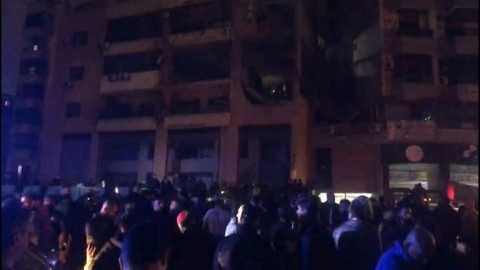 People gather in the street at site of explosion in Beirut's southern suburbs