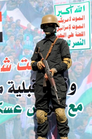 A Huthi fighter in front of a banner which reads in Arabic: "Death to America, Death to Israel" 