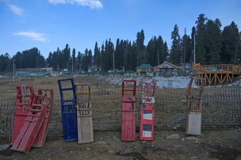 Sleds are seen resting on a fence near ski slopes without snow, with tourist bookings plunging by as much as three-quarters