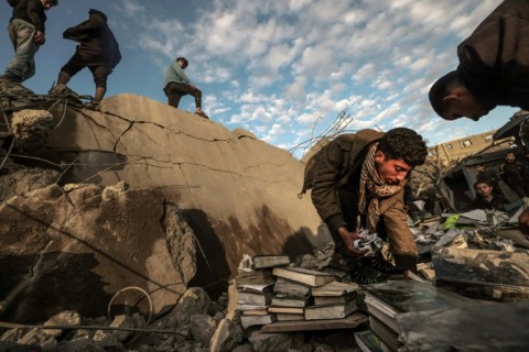 Palestinian youthd recover books from the rubble of a mosque and buildings in Rafah