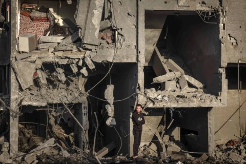 A Palestinian man stands in front of a destroyed building in Rafah