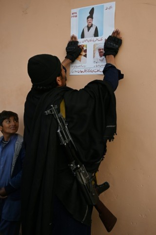 A man puts up a poster for an independent candidate in Mianwali on January 16, 2024