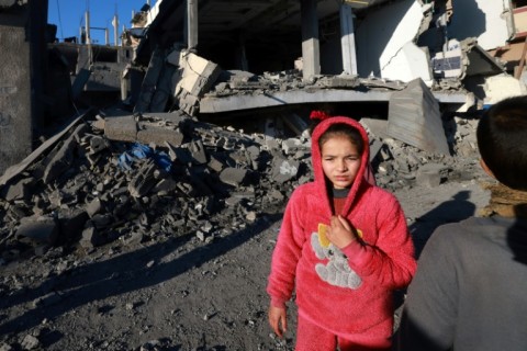 A child stands in front of a building destroyed in Israeli bombardment on Rafah in the southern Gaza Strip on February 4, 2024