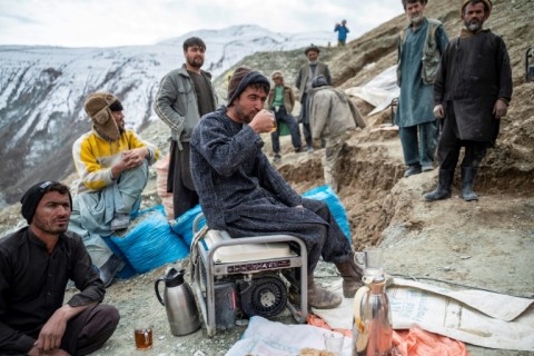 A group of Afghan miners take a break outside their gold mine