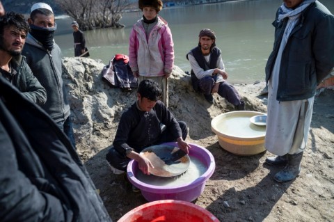 An Afghan youth (C) pans for gold in the traditional way at a gold mine along the Kokcha River