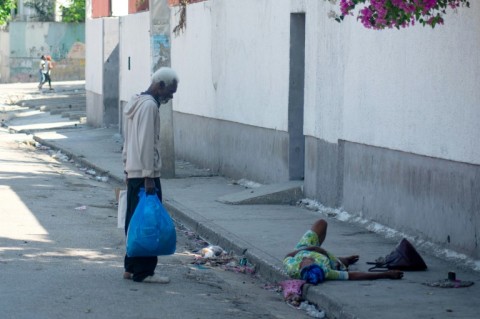 An elderly woman, who was shot in the foot, lies in the street in Port-au-Prince, Haiti