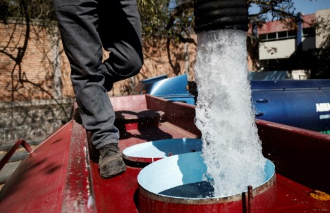 A worker fills a tanker truck with drinking water to distribute in Mexico City 