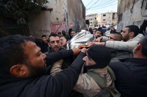 Palestinians move the body of a man killed in an Israeli raid early Thurday on a refugee camp in the West Bank
