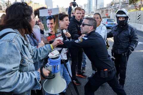 Activists argue with an Israeli policeman as they block the Ayalon Highway during a protest calling for the hostages' release in Tel Aviv on Wednesday