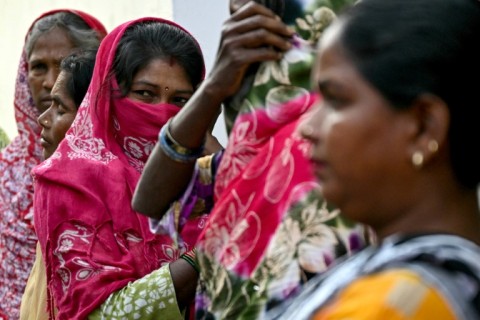 Women wait to cast their votes at a polling station in Haridwar, in India's Uttarakhand state Friday