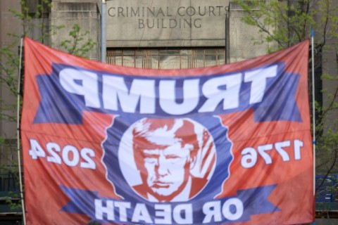 Supporters of former US President Donald Trump hold up a Trump-themed flag outside of Manhattan Criminal Court