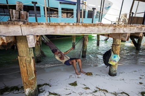 A man lies in a hammock on a beach in Cancun, Mexico
