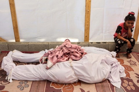 A Palestinian girl sits by the retrieved bodies of victims killed in a strike on north Gaza's Al-Shati refugee camp