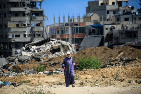 A Palestinian man walks along a dirt road past destroyed buildings in southern Gaza's Khan Yunis