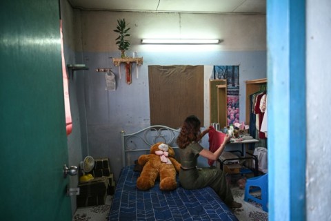 "Khaing", a former teacher, beside a large teddy bear gifted to her by a friend who knew she was feeling lonely
