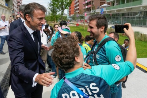 Emmanuel Macron poses for a selfie as the French president meets volunteers at the Athletes' Village for the Paris Olympics