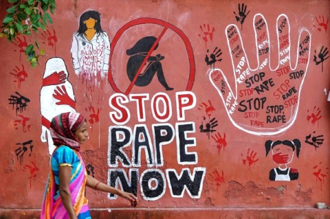 A woman walks past a mural painted condemning the rape and murder of a doctor in India's West Bengal state