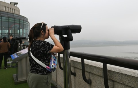 Visitors use binoculars to look at the North Korean side of the heavily militarised border that separates it from the South