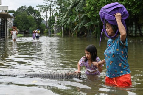 People wade through a street that flooded by heavy rains in Rizal province, east of Manila
