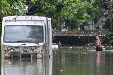 A woman wades through a street flooded by heavy rains from Tropical Storm Trami in Rizal province