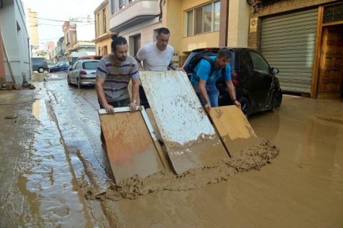 Residents tried to clean a street covered in mud after flash floods hit the town of Alfafar