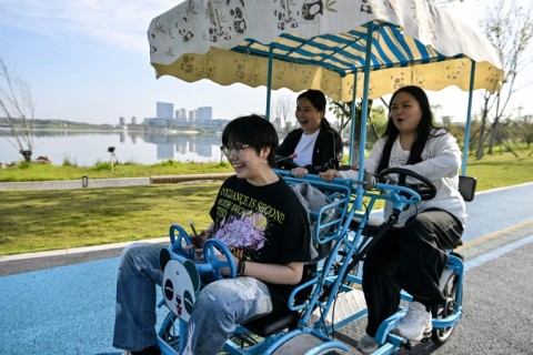 Yang Chi'ao (R) rides a cart through a park as part of training at a weight-loss camp in Chengdu