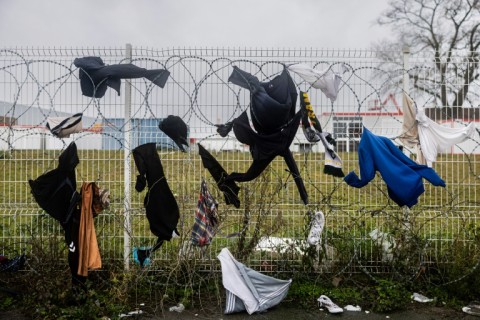 Drenched clothes hang on a barbed wire fence nearby