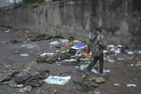 A young Congolese boy rummages through a discarded pile of military paraphernalia 
