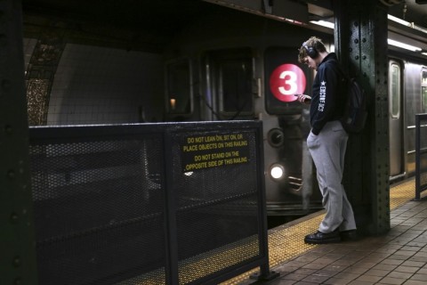 A person stands next to a safety barrier on a subway platform in New York 