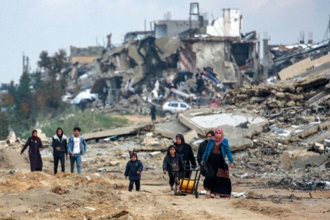 Palestinians walk along a destroyed road in Beit Lahia, in the war-ravaged north of the Gaza Strip