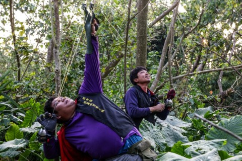 Hunter Wu Cheng-hua aims his slingshot at an iguana in a tree in Pingtung