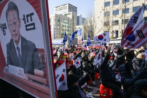 A defaced poster (L) of opposition Democratic Party leader Lee Jae-myung is displayed alongside supporters of South Korean leader Yoon Suk Yeol, during a rally near the Central District Court in Seoul on February 20, 2025