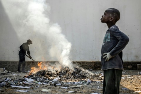 A man uses a stick to sift through the smoldering remains of boxes and materials left behind by looters in Bukavu