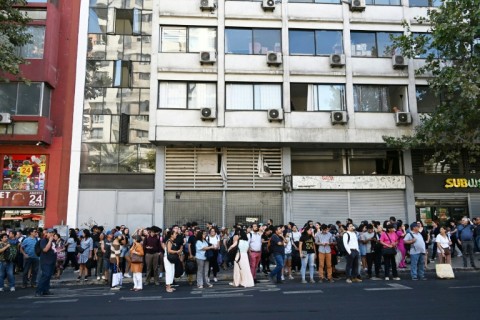 People wait at a bus stop during a blackout in Santiago on February 25, 2025