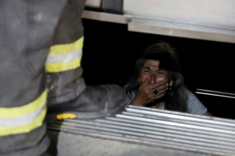 An elderly person trapped in an elevator is assisted by firefighters during a blackout in Santiago
