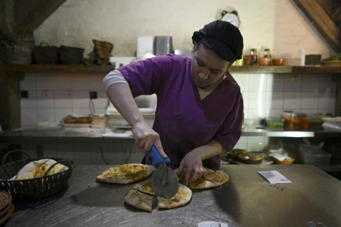 A cook cuts flatbread straight from the oven at Kosovo's Ethno House restaurant