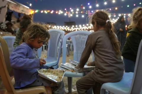 Palestinian children eat their food during a group Iftar meal, the evening meal with which Muslims end their daily fast at sunset, in Gaza City 