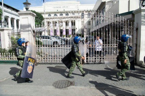 Police in anti-riot gear walk past the gates of the Supreme Court in Manila on Wednesday