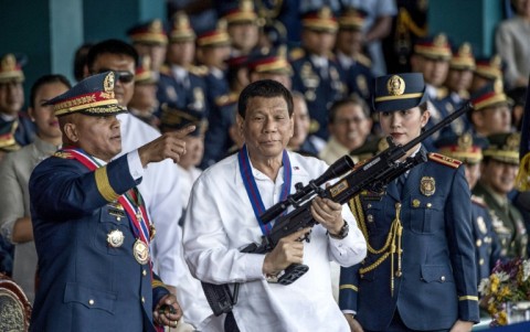 Former Philippine president Rodrigo Duterte, shown holding a rifle in 2018, faces charges over his drug war