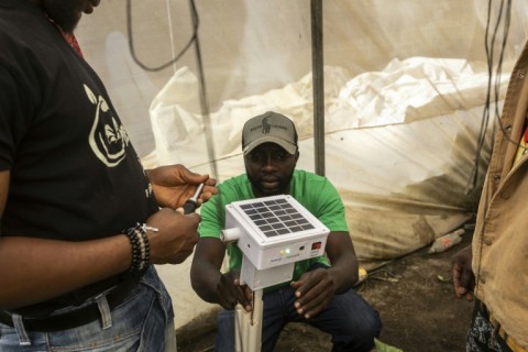 Green Eden workers open a 'ScareGrow` hardware device in a greenhouse using local agri-tech 