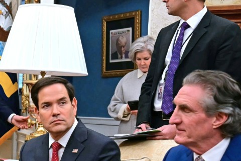 A front page of The New York Post featuring President Donald Trump's 2023 mugshot hangs on a wall outside the Oval Office