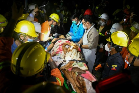 Medics treat a victim pulled from the rubble of the destroyed condominium block