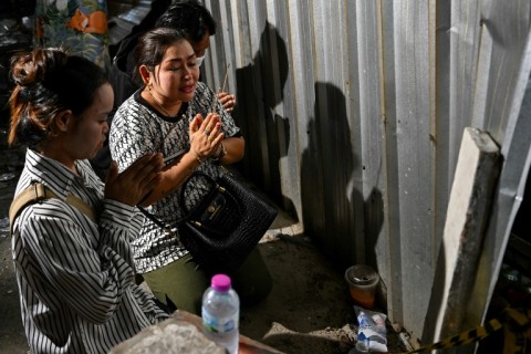 Women offer prayers and burn incense sticks near the site of building under construction that collapsed in Bangkok